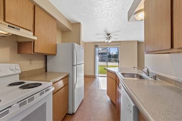 Spokane apartment for rent - A kitchen with a white stove top oven and a white refrigerator.