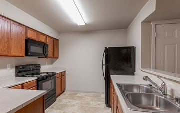 Spokane Valley apartment for rent - A kitchen with a black refrigerator and a black microwave.