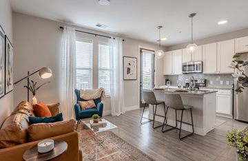 Columbus apartment for rent - A modern living room with a brown sofa and a kitchen in the background.