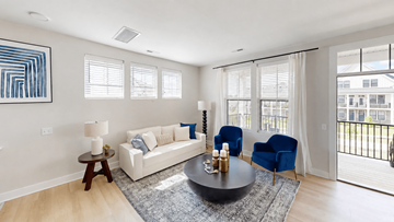 Akron apartment for rent - A living room with a white couch, blue chairs, and a painting on the wall.