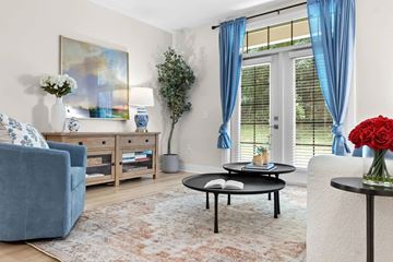 Akron apartment for rent - A living room with a blue couch, a coffee table, and a painting on the wall.