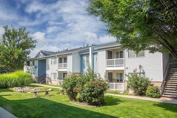 Sandy apartment for rent - A sunny day at a residential complex with a blue sky and greenery.