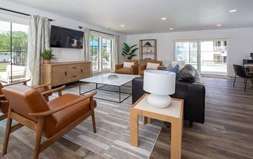 Sandy apartment for rent - A living room with a brown leather chair and a white table.