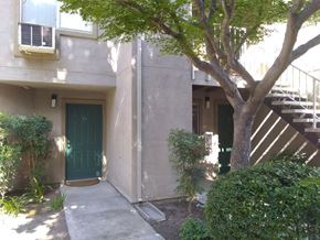 Modesto apartment for rent - Colonial Farms Apartments - ground floor apartment entrance with concrete walkway up to door, with trees and bushes