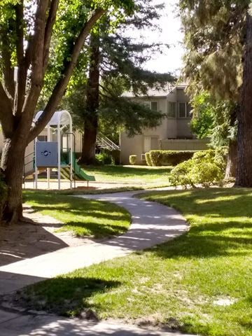 Modesto apartment for rent - A playground with a slide and a green lawn.