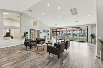 Las Vegas apartment for rent - A spacious living room with dark brown sofas and a large window overlooking a pool.
