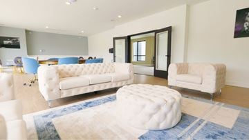 West Orange apartment for rent - A white tufted ottoman sits in the middle of a blue rug in a living room.