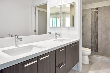 A bathroom with a white sink and brown cabinets.