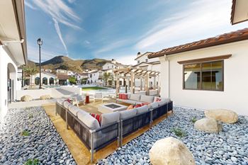 A patio with a couch and a table with a mountain in the background.