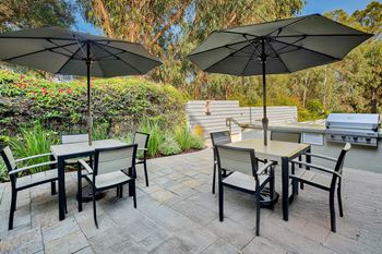 A patio with a table and chairs under umbrellas.