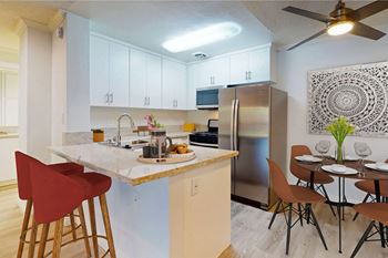 A kitchen with a breakfast bar and a stainless steel refrigerator