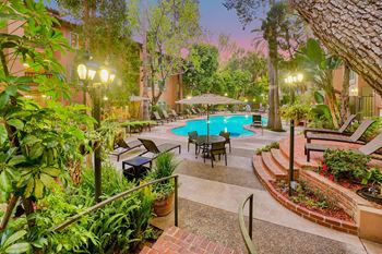 A backyard with a swimming pool and a patio with tables and chairs