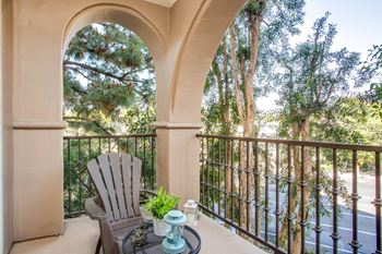 A balcony with a chair and a view of a tree