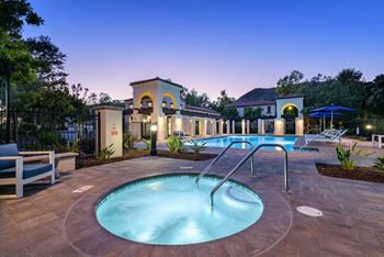 A swimming pool with chairs and a fountain in front of a house