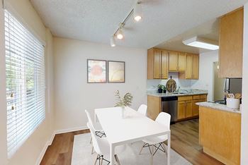 A dining room and kitchen with a white table and chairs