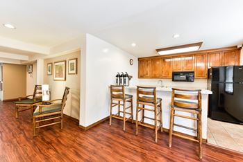 A kitchen with a bar with three chairs and a table