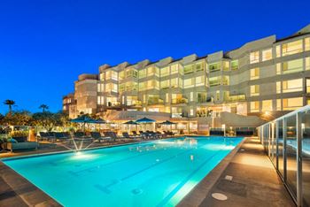 A large swimming pool in front of a building at night.