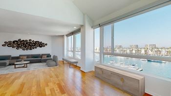A living room with a view of the water and boats.