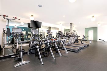 A gym with a variety of equipment including treadmills, stationary bikes, and weight machines.