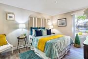 Victorville apartment for rent - A bedroom with a bed, nightstand, and a chair at Mountain Vista, Victorville, CA