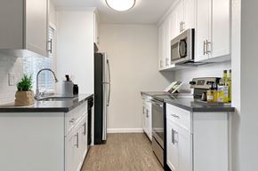 Pleasanton apartment for rent - A kitchen with white cabinets and black countertops at Valley Plaza Villages, California, 94566