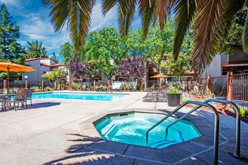A pool surrounded by palm trees and patio furniture.