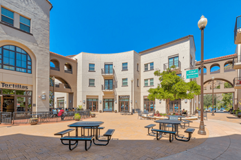 A city square with tables and benches in front of a building