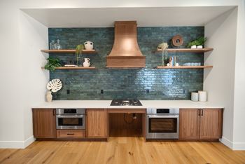 A kitchen with a blue brick wall and wooden cabinets.