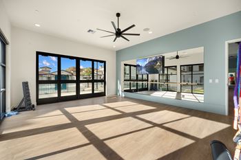 A room with a ceiling fan and a large window overlooking a balcony.