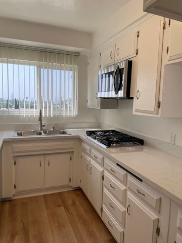 West Hollywood apartment for rent - an example of a kitchen with white cabinets and a stove and a microwave