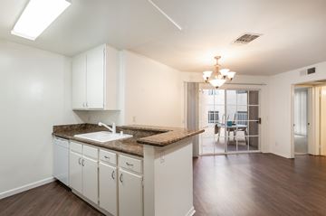 Los Angeles apartment for rent - a kitchen with white cabinets and granite counter tops and a living room with a door