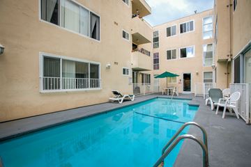 Los Angeles apartment for rent - a swimming pool with chairs and an umbrella in front of a building