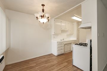 Los Angeles apartment for rent - an empty kitchen with white cabinets and a white stove top oven