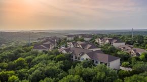Austin apartment for rent - a neighborhood of houses surrounded by trees with a sunset in the background at The Verandah, Austin, 78726