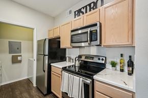 San Antonio apartment for rent - A kitchen with wooden cabinets and a black stove top oven.