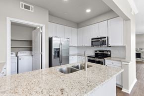 Georgetown apartment for rent - A kitchen with white cabinets and a granite counter top at Waters Edge Apartment Homes, Georgetown, 78626