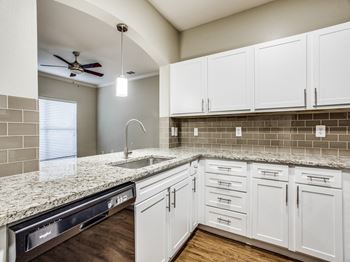 A kitchen with white cabinets and granite countertops