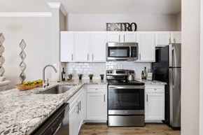 Austin apartment for rent - a white kitchen with stainless steel appliances and granite counter tops at Sonterra Apartment Homes, Austin, Texas