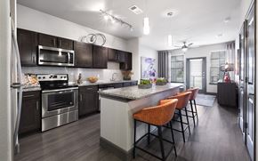 Hutto apartment for rent - a kitchen with stainless steel appliances and a large island with chairs at North Creek, Texas, 78634