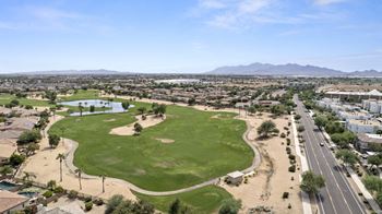 An aerial view of a golf course with a city in the background