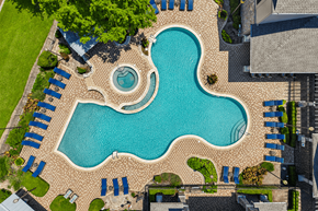 Round Rock apartment for rent - A large blue swimming pool surrounded by a brick patio and lounge chairs.