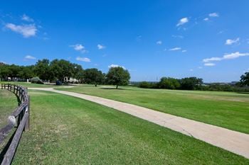 A walking path through a park with grass and trees