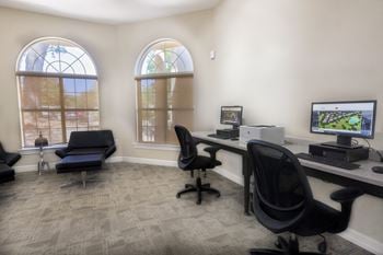 An office with two windows and a desk with a computer