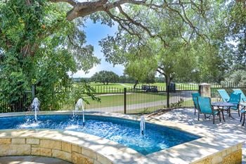 A swimming pool with water fountains and a table and chairs