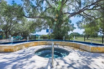 A small pool with a stone wall and a tree