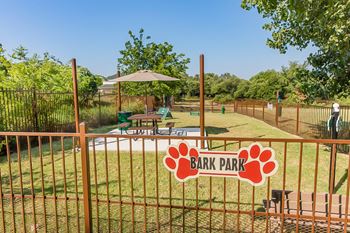 A park with a fence and a sign for bark park