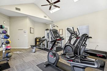 The gym has plenty of exercise equipment and a ceiling fan