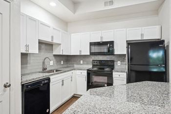 A kitchen with granite counter tops and black appliances