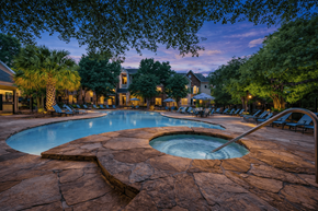 Austin apartment for rent - A large outdoor pool surrounded by trees and lounge chairs.