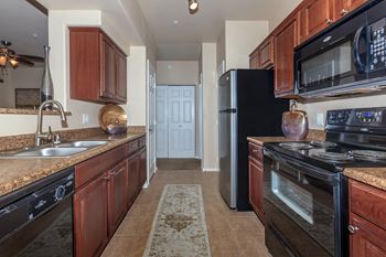 A kitchen with black appliances and brown cabinets